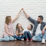 Family with young children forming a roof with their hands