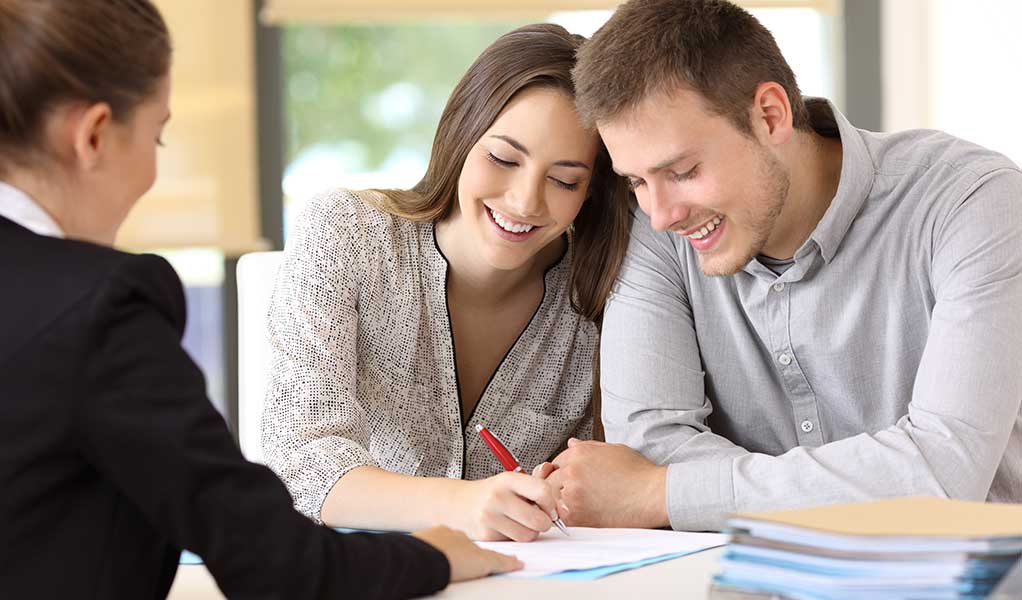 Young Couple signing loan docs for a home purchased with a bridge loan
